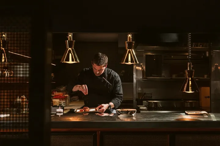 A chef cooking at a station under warm lamps.